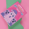 Holiday card with pink background featuring cartoon ghosts. Main ghost wears purple Santa hat. Text reads "WISHING YOU A HAUNTED HOLIDAY" in colorful, playful font. Overall cute and spooky design blending Halloween and Christmas themes. Inside message: "Eat, Drink, and Be Scary.