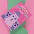 Holiday card with pink background featuring cartoon ghosts. Main ghost wears purple Santa hat. Text reads "WISHING YOU A HAUNTED HOLIDAY" in colorful, playful font. Overall cute and spooky design blending Halloween and Christmas themes. Inside message: "Eat, Drink, and Be Scary.