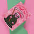 Quirky Christmas card featuring grim reaper in Santa hat. Pink background with bats, snowflakes, skull motifs. Text reads 'Grave Tidings We Bring'. Humorous blend of holiday cheer and gothic aesthetic. Perfect for alternative Christmas greetings.