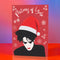 A festive greeting card featuring an illustration of Robert Smith from The Cure, wearing a Santa hat. The card has a red background with white snowflakes and the text "Pictures of Yule" at the top, playfully referencing the song "Pictures of You." The card merges gothic and holiday themes for a unique seasonal twist.