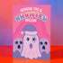 Holiday card with pink background featuring cartoon ghosts. Main ghost wears purple Santa hat. Text reads "WISHING YOU A HAUNTED HOLIDAY" in colorful, playful font. Overall cute and spooky design blending Halloween and Christmas themes. Inside message: "Eat, Drink, and Be Scary.