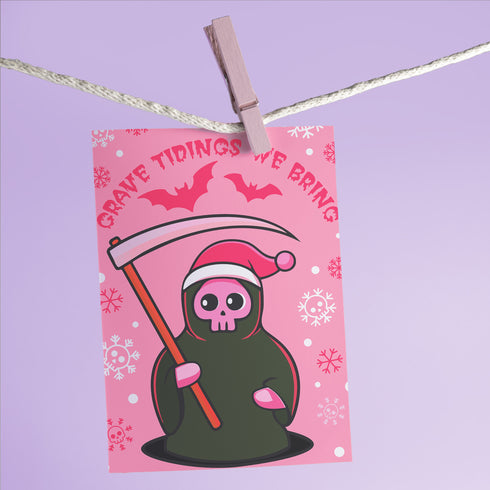 Quirky Christmas card featuring grim reaper in Santa hat. Pink background with bats, snowflakes, skull motifs. Text reads 'Grave Tidings We Bring'. Humorous blend of holiday cheer and gothic aesthetic. Perfect for alternative Christmas greetings.