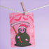 Quirky Christmas card featuring grim reaper in Santa hat. Pink background with bats, snowflakes, skull motifs. Text reads 'Grave Tidings We Bring'. Humorous blend of holiday cheer and gothic aesthetic. Perfect for alternative Christmas greetings.