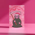 Quirky Christmas card featuring grim reaper in Santa hat. Pink background with bats, snowflakes, skull motifs. Text reads 'Grave Tidings We Bring'. Humorous blend of holiday cheer and gothic aesthetic. Perfect for alternative Christmas greetings.