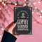 A black holiday card featuring gothic-style text that reads "Have Yourself a Gothy Merry Christmas." The design includes a skull wearing a Santa hat, bats, and ornate decorative borders, combining a dark, spooky aesthetic with festive holiday elements.