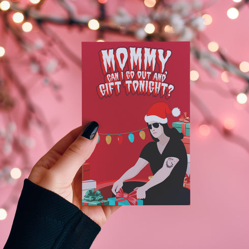 Punk rock Christmas card featuring Glenn Danzig-inspired figure in Santa hat, surrounded by presents. Text reads "Mommmy, can I go out and gift tonight?" Perfect for alternative holiday greetings.