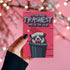 A humorous holiday card featuring a cartoon possum popping out of a trash can, wearing a Santa hat with fangs bared. The text at the top reads "It's the most trashiest time of the year," adding a playful and quirky twist to the holiday season.