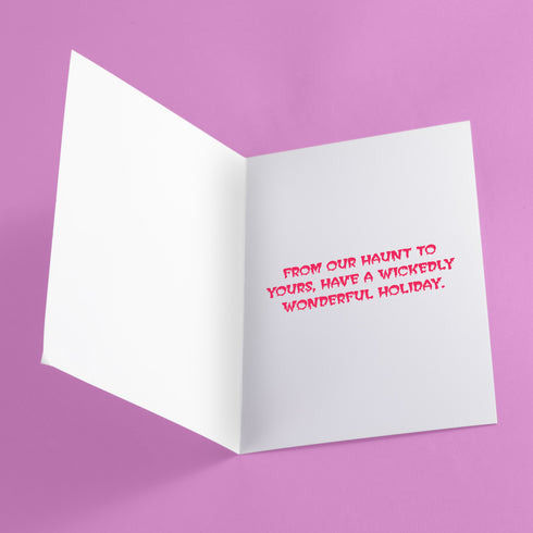 Quirky Christmas card featuring grim reaper in Santa hat. Pink background with bats, snowflakes, skull motifs. Text reads 'Grave Tidings We Bring'. Humorous blend of holiday cheer and gothic aesthetic. Perfect for alternative Christmas greetings.