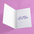 Holiday card with pink background featuring cartoon ghosts. Main ghost wears purple Santa hat. Text reads "WISHING YOU A HAUNTED HOLIDAY" in colorful, playful font. Overall cute and spooky design blending Halloween and Christmas themes. Inside message: "Eat, Drink, and Be Scary.