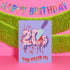 A 5x7 birthday card with a horror-comedy design. The front features the word "20s" in pink gooey lettering with a bloody knife stabbing through it, surrounded by red blood splatter. Below it reads "YOU KILLED IT!" in dripping red font, set against a purple background with a rainbow foil tinsel curtain behind it. Inside, the right panel says "HERE'S TO THE NEXT VICTIM: YOUR THIRTIES!" with dripping red blood at the top and a pink cherry garland background.