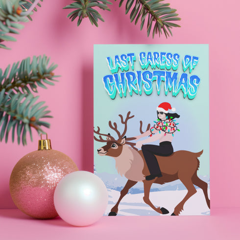 A humorous holiday card featuring an illustration of Glenn Danzig from the Misfits riding a reindeer, wearing a Santa hat and wrapped in Christmas lights. The text at the top reads "Last Caress of Christmas" in icy blue letters, referencing the iconic Misfits song. The background depicts a snowy winter scene, combining punk rock and festive elements for a playful twist.