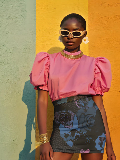 High-waisted black mini skirt with a bodycon fit, featuring a bold allover floral graphic print in pink and blue. Made of stretchy polyester-spandex blend with a smooth finish. Styled in various festival and streetwear looks. Available in sizes XS to XL.