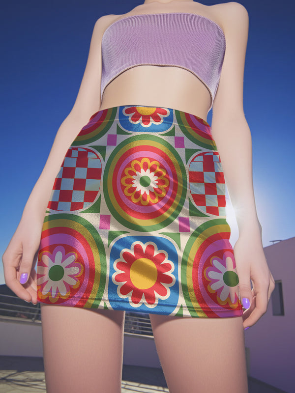 A vibrant bodycon mini skirt featuring a structured grid of retro geometric medallions. The pattern includes concentric circles in red, yellow, and blue, stylized daisy flower motifs, and red and white checkered squares. The skirt has a high-waist elastic band and a smooth, matte performance knit texture. The background is a neutral off-white. This maximalist design utilizes saturated primary colors to create a 70s-inspired psychedelic aesthetic. No purple or navy is present in the print.