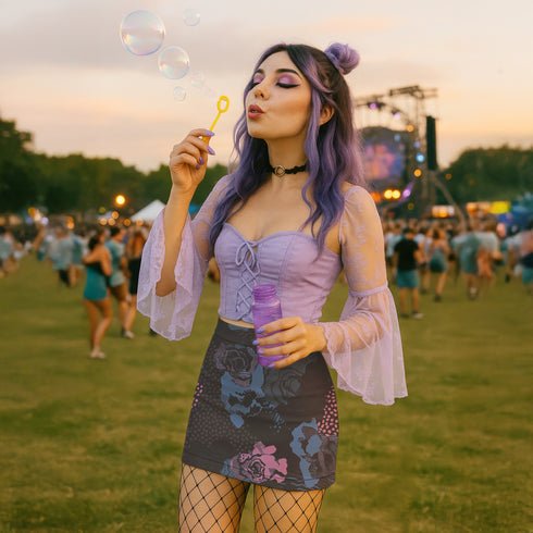 High-waisted black mini skirt with a bodycon fit, featuring a bold allover floral graphic print in pink and blue. Made of stretchy polyester-spandex blend with a smooth finish. Styled in various festival and streetwear looks. Available in sizes XS to XL.