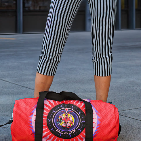 Red cylindrical roller skating duffle bag with black straps, featuring a prominent circular emblem with a colorful Baphomet design and "Hail Skatin" text. Includes mesh side pocket and adjustable padded shoulder strap.