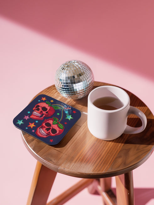 Square navy blue coasters featuring vibrant red cherry skulls with green stems and colorful star designs. Gothic drink coasters for maximalist home bar decor, whimsigoth table accessories perfect for weird decor enthusiasts and cocktail lovers.