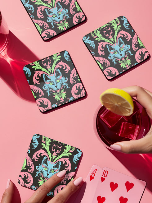 Square coasters featuring psychedelic blue cats with green eyes surrounded by baroque pink and green flourishes on black backgrounds. Gothic maximalist drink coasters for cat lovers, weird barware accessories, funky eclectic home decor, whimsigoth design.