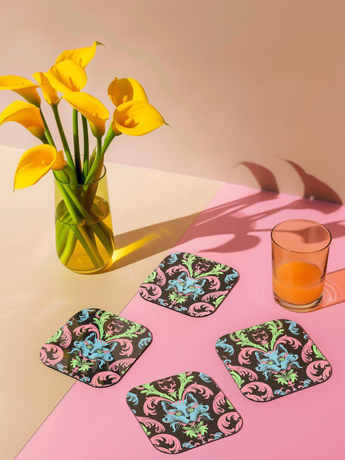 Square coasters featuring psychedelic blue cats with green eyes surrounded by baroque pink and green flourishes on black backgrounds. Gothic maximalist drink coasters for cat lovers, weird barware accessories, funky eclectic home decor, whimsigoth design.