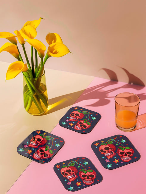 Square navy blue coasters featuring vibrant red cherry skulls with green stems and colorful star designs. Gothic drink coasters for maximalist home bar decor, whimsigoth table accessories perfect for weird decor enthusiasts and cocktail lovers.