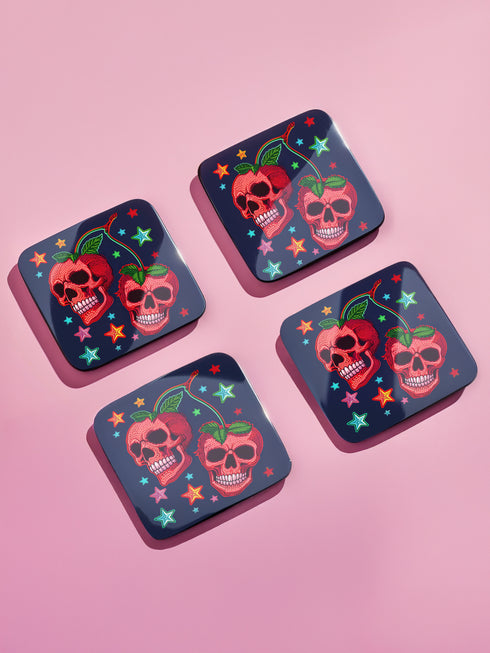 Square navy blue coasters featuring vibrant red cherry skulls with green stems and colorful star designs. Gothic drink coasters for maximalist home bar decor, whimsigoth table accessories perfect for weird decor enthusiasts and cocktail lovers.