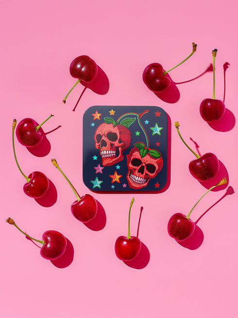 Square navy blue coasters featuring vibrant red cherry skulls with green stems and colorful star designs. Gothic drink coasters for maximalist home bar decor, whimsigoth table accessories perfect for weird decor enthusiasts and cocktail lovers.