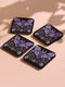 Square coasters featuring lavender-purple bats with folk art floral designs against black backgrounds. Pastel goth drink coasters, kawaii bat home decor, whimsigoth barware accessories, gothic floral table protection for weird home aesthetics.
