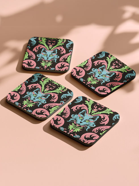 Square coasters featuring psychedelic blue cats with green eyes surrounded by baroque pink and green flourishes on black backgrounds. Gothic maximalist drink coasters for cat lovers, weird barware accessories, funky eclectic home decor, whimsigoth design.