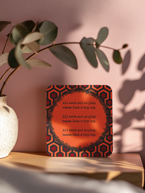 Four-piece horror movie coaster set featuring The Shining and Carrie designs in black, red, and orange with iconic quotes and imagery from the films. Cork-backed hardboard construction.