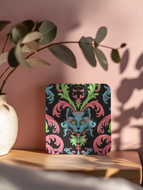 Square coasters featuring psychedelic blue cats with green eyes surrounded by baroque pink and green flourishes on black backgrounds. Gothic maximalist drink coasters for cat lovers, weird barware accessories, funky eclectic home decor, whimsigoth design.