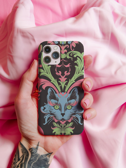 Phone case featuring baroque-style blue cat with green eyes surrounded by mint green foliage and pink flourishes on black background, Victorian-inspired desig