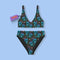 High-waisted bikini set featuring an all-over pattern of neon blue skulls with pink bows, pastel stars, and purple cherries on a dark olive green background. The top has a scoop neckline with wide straps, and the bottoms offer full coverage. A bold, punk-inspired swim look perfect for alternative fashion lovers and dopamine dressers.