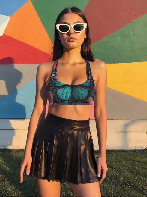 Scoop-neck bikini top with wide straps and a gothic butterfly wing design in deep jewel tones—teal, burgundy, and violet—set against black. Sports-bra style silhouette with bold symmetrical wing details across the chest. Floating above a turquoise pool, this swim top serves dreamy alt-girl energy for pool witches, celestial babes, and butterfly goths alike.