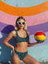 Two-piece high-waisted bikini set featuring an all-over print of blue skulls with purple bows and multicolored stars on a dark background. Includes a deep V-neck bikini top with wide straps and matching high-rise bottoms. Made from soft, stretchy fabric with a smooth black inner lining. The design combines bold, edgy graphics with a flattering retro-inspired silhouette.