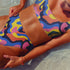 Scoop-neck bikini top with wide straps, featuring a bold psychedelic wave print in pink, yellow, blue, orange, and navy. Designed in a sports-bra style silhouette with supportive coverage and a vibrant Y2K vibe. Floating against a turquoise pool background, this top brings festival energy, dopamine brights, and funky retro flair to your swimwear drawer.