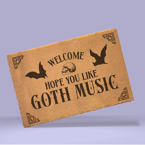 Tan coir doormat featuring "Welcome, Hope You Like Goth Music" in black text, with bat and skull imagery and gothic-style corner decorations.