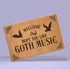 Tan coir doormat featuring "Welcome, Hope You Like Goth Music" in black text, with bat and skull imagery and gothic-style corner decorations.