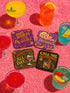 A 4-piece retro coaster set featuring colorful 70s-style cocktail graphics with playful drink quotes: "More Bubbles Less Trouble," "I Make Pour Decisions," "Cabernet All Day," and "Call Me Old-Fashioned." These 3.75” square coasters are made of Masonite with a glossy finish and cork backing—perfect for funky bar carts, dopamine décor, and retro hostess gifts.