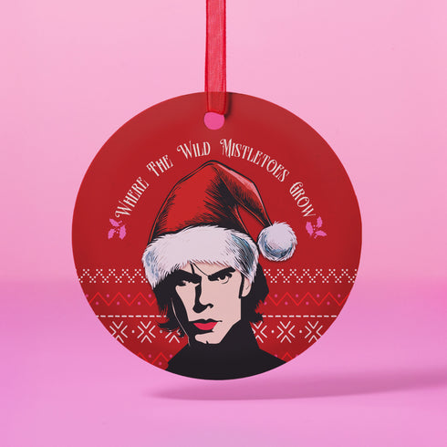 "Round red metal Christmas ornament featuring Nick Cave in black and white with Santa hat, Nordic patterns, and 'Where The Wild Mistletoes Grow' text, suspended by red ribbon