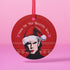 "Round red metal Christmas ornament featuring Nick Cave in black and white with Santa hat, Nordic patterns, and 'Where The Wild Mistletoes Grow' text, suspended by red ribbon