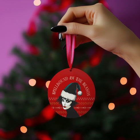 Round red metal Christmas ornament featuring Siouxsie Sioux in black and white with Santa hat, geometric patterns, and 'Spellbound by the Season' text, suspended by red ribbon