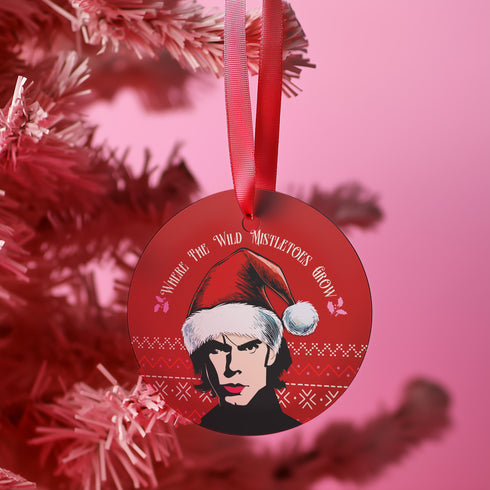 "Round red metal Christmas ornament featuring Nick Cave in black and white with Santa hat, Nordic patterns, and 'Where The Wild Mistletoes Grow' text, suspended by red ribbon
