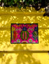 A rectangular doormat featuring a vibrant hot pink background with a high-fidelity tapestry-style print of three large, detailed beetles. The central beetle is emerald green and gold with navy accents, flanked by two side-profile beetles in ochre and deep blue. Stylized teal and yellow sunburst flowers and small sage green leaves are scattered throughout the design. The mat has a sleek black-trimmed edge and a visible flat, durable polyester texture mimicking intricate needlework.