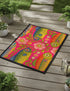Rectangular indoor outdoor doormat featuring a vibrant hot pink background with a symmetrical maximalist pattern. The design showcases stylized sardines in yellow, lime green, and cobalt blue swimming horizontally towards a central vertical axis of blooming pale pink flowers and green vines. The imagery mimics the texture of vintage needlepoint embroidery but is a flat print on polyester. The mat is framed by a sleek black trim and features a non-slip rubber backing for safety.