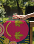 A rectangular doormat featuring a large hot pink smiley face on a deep teal background. The smiley face has green cannabis leaves for eyes and a yellow stitched-style smile. The central face is surrounded by stylized green foliage arches and concentric circles in pink, yellow, and white, resembling abstract flowers. The design mimics a vintage needlepoint or tapestry texture but is a flat print. The mat has a solid black trim border.