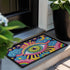 Rectangular entryway doormat with a deep purple background printed in a 2D faux embroidery illusion. The symmetrical mandala centers on a large green, pink, and white evil eye with golden yellow sunburst lines radiating outward. The corners hold textured cyan clouds, yellow crescent moons, and stars, with a scalloped floral motif along the lower edge. Finished with black trim and a non-slip rubber backing. Psychedelic celestial maximalist home decor and protective evil eye welcome mat for bold, eclectic ent