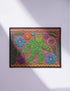 A rectangular flat-printed doormat featuring a faux-tufted, trompe-l'œil texture design. The background is a vibrant hot pink, bordered by a wavy yellow line. In the center is a bright green, smiling Bigfoot or Sasquatch figure with long shaggy hair. Surrounding the cryptid are highly detailed, colorful faux-embroidered floral motifs including blue, orange, and purple daisies, alongside green fern fronds and leaves. The mat is finished with a solid black fabric trim around the outer edge.