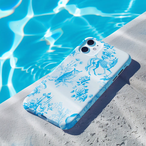 Phone case with a blue and white toile pattern featuring skeletons, owls, and floral motifs. Dual-layer protection available in glossy or matte finish.