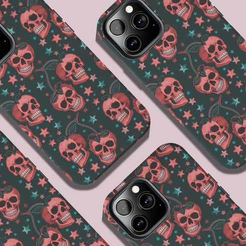 Phone case featuring coral pink apple skulls with green stems and multicolored stars on black background. Gothic alternative design with pastel accents.
