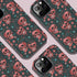 Phone case featuring coral pink apple skulls with green stems and multicolored stars on black background. Gothic alternative design with pastel accents.