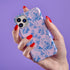 Phone case with pink background featuring blue toile print of skeletons, peacocks, owls, and roses. Victorian-inspired design with gothic elements. Dual-layer protection for various smartphone models.